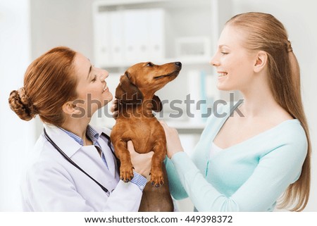 médecine, soins aux animaux de compagnie et concept de personnes - femme heureuse et médecin vétérinaire tenant un chien dachshund à la clinique vétérinaire