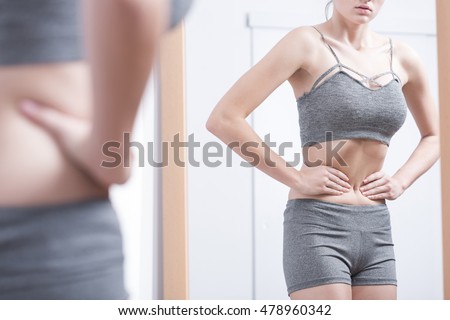 Young woman in sporty underwear looking at her refletion in the mirror Foto stock © 