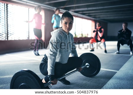 Fit healthy woman exercising, sitting at floor looking at camera, getting ready to lift weight
