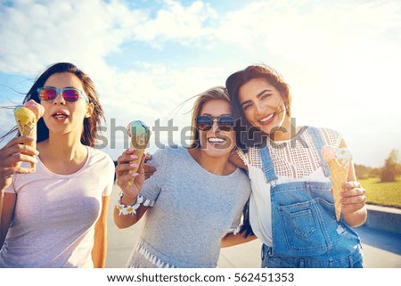 Tres novias disfrutando de una delicia veraniega caminando en brazo por un paseo comiendo helados italianos coloridos en cono