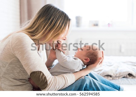 Similar – Foto Bild Blonde Mutter hält ihr bezauberndes fröhliches kleines Baby im Arm. Nettes Kleinkind Kind in die Kamera schauen und lächelnd zu Hause