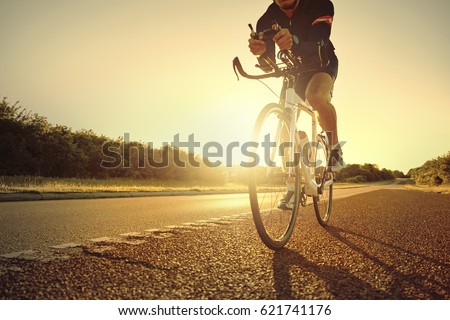 The sportsman moving on a bicycle on the empty highway in sunset.