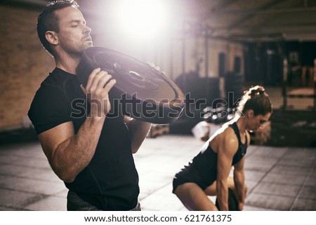 Young sportive people having hard workout with heavy weight disks in gym. 