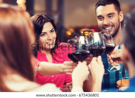 lazer, celebração, bebidas, pessoas e férias conceito - casal feliz e amigos tilintando copos de vinho no restaurante