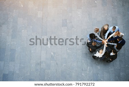 Vista panorámica de un equipo de hombres de negocios unidos, con las manos juntas, en medio de un embotellamiento en el vestíbulo de un moderno edificio de oficinas