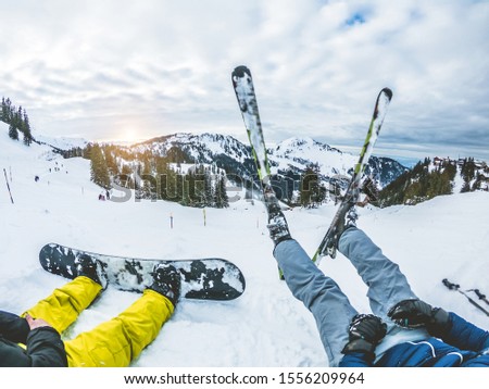 Dos amigos con snowboard y ski viendo la puesta de sol en las altas montañas - Joven atleta divirtiéndose en la semana blanca - El deporte invernal extremo, la aventura, el viaje y el concepto de vacaciones - Enfoque en los pies a la izquierda