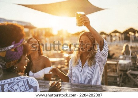 Happy girls having fun drinking cocktails at bar on the beach - Soft focus on african girl face