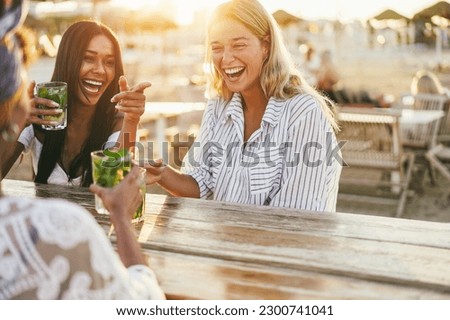 Niñas felices divirtiéndose bebiendo cócteles en el bar de la playa - Concéntrate en las manos africanas sosteniendo vidrio