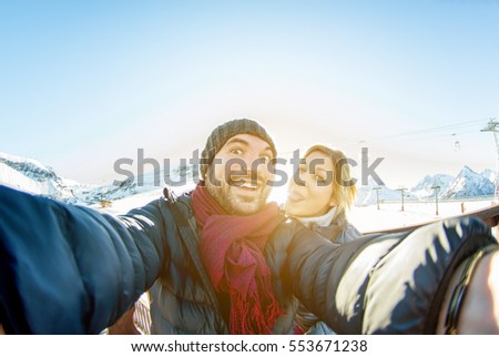 Casal jovem fazendo selfie neve resort fundo montanha com telefone celular - Turista rindo e fazendo rostos emocionais engraçados na câmera do smartphone - Conceito de férias - Foco nele - Filtro quente