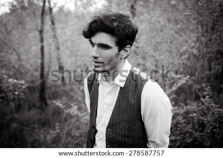 outdoor portrait of a very beautiful sexy young man, dark hair, posing in an old courtyard in classic suit