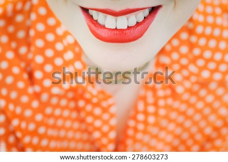 close-up portrait outdoors young beautiful girl in an orange hipster blonde bright cheerful polka dot blouse , smiling red plump lips on the background of green grass 
with white teeth