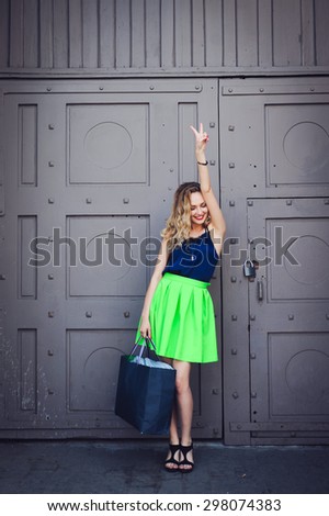 close-up portrait of a beautiful young blonde hipster girl with curly hair with a package from the store, selling, smiling and posing