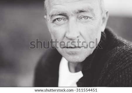 Mature handsome gray-haired man close up looking at the camera and posing