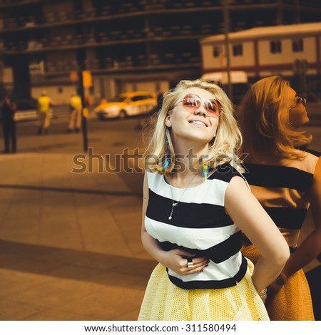 close-up portrait of a beautiful charming girl hipster blonde in a striped blouse and yellow skirt laughing and posing with full lips