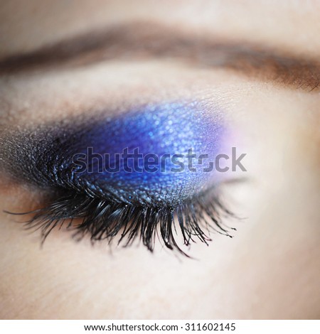 close-up \
blue eye of a beautiful sexy young  with lilac and pink hair  eyelash makeup and shadows