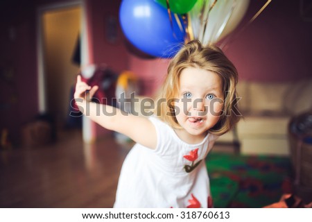 portrait of little baby girl at home on the day of birth in a dress with colorful balls smiles and laughs