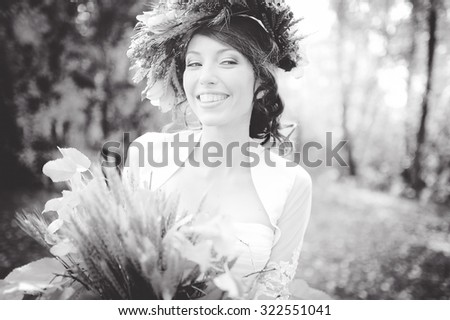 close-up portrait of a beautiful young sexy girl brunette bride with flowers in her hair look attractive in a white dress on a background of autumn forest and leaves posing and smiling