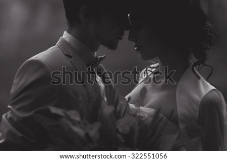 close-up portrait of wedding couples in love hipsters bride in a white dress with flowers and groom in a suit with glasses and bow tie smiling  posing touching embrace on a background of autumn forest