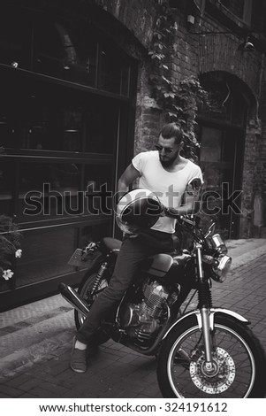 young guy with a beard and mustache with sunglasses and jacket posing on the street  vintage man, fashion men, hipster street casual \
a motorcycle