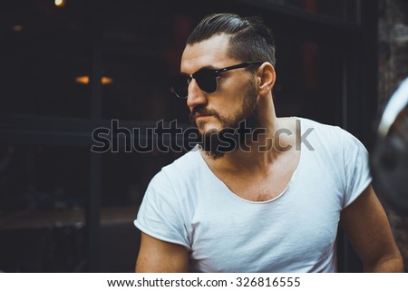 portrait macho sex appeal young guy with a beard and mustache and white T-shirt posing on the street vintage man, fashion men, hipster street   close-up