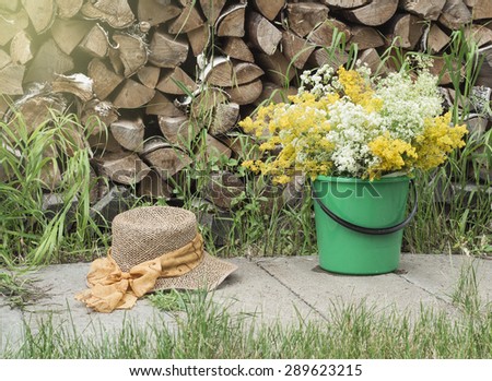 Summer at the cottage. A bouquet of flowers in the bucket. Women\'s straw hat.