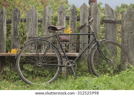 Old bike standing at the wooden fence. Still life of village life.