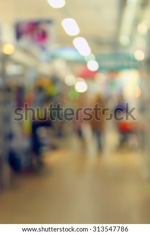 Blurred background: the lights in the supermarket, people, advertising