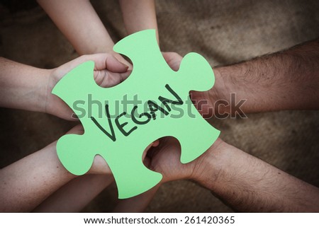 Cooperation - Jigsaw Puzzles in Teams Hands spelling out vegan