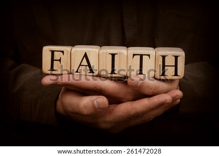 Building blocks in hands spelling out Faith