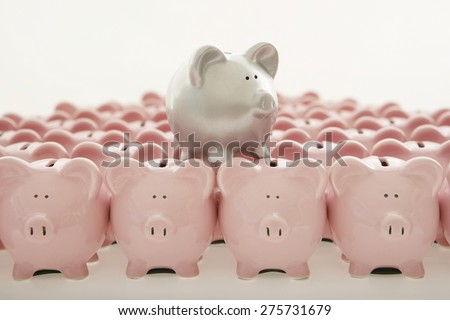 Silver piggy bank among lots of pink ones