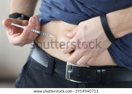 Man injects himself in stomach with an injection of insulin. How to properly give yourself subcutaneous injection in your stomach concept