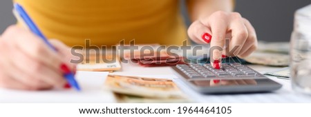 Woman is counting on calculator and writing with pen in notebook closeup Foto stock © 