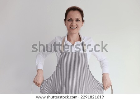 Young brunette housewife puts on striped apron smiling with satisfaction. Inspired female blogger prepares to shoot video for cooking blog Foto stock © 