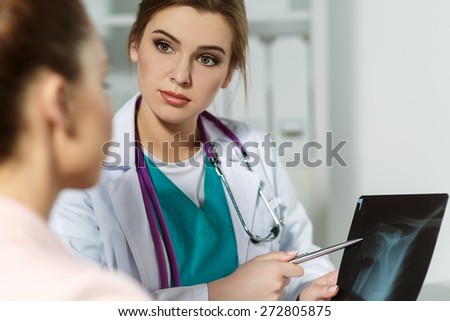 Medicine doctor with serious face explains to patient diagnosis pointing to x-ray picture. Patient listening carefully doctors recommendations. Medical concept.