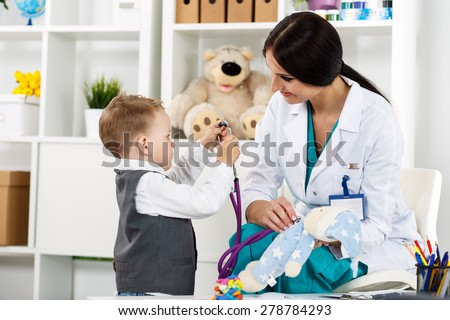 Family doctor examination. Little child visiting pediatrician playing with stethoscope. Beautiful female medical freckled doctor  communicating with cute young patient. Paediatrics medical concept