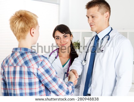 Male doctor shaking hands with female patient. Partnership, trust and medical ethics concept. Handshake with satisfied client. Thankful handclasp for excellent treatment.