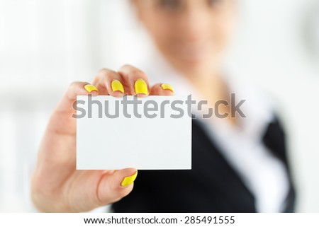 Businesswoman in suit hand holding blank calling card. Female hand showing white visiting card in camera closeup. Partners contact information exchange concept. Introducing gesture at formal meeting