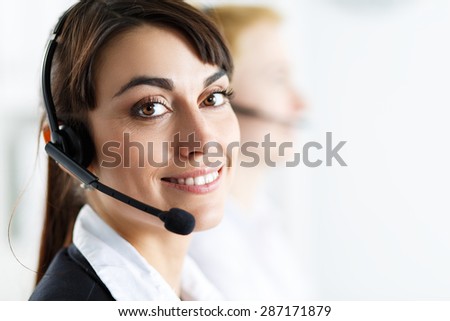 Female call center service operator at work. Portrait of smiling pretty female helpdesk employee with headset at workplace. Effective and efficient business information, help and support concept