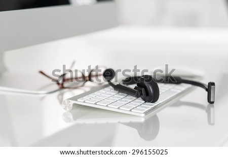Call center service operator\'s empty working place. Headset, glasses, keyboard and monitor at helpdesk employee workplace. Effective and efficient business information, help and support concept