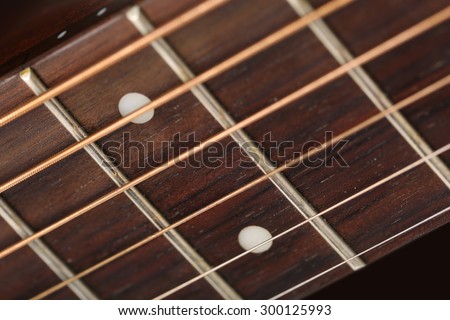 Empty wooden rosewood fingerboard of classic acoustic guitar closeup. Six strings, free frets and fretboard dots. Musical instruments shop or learning school concept