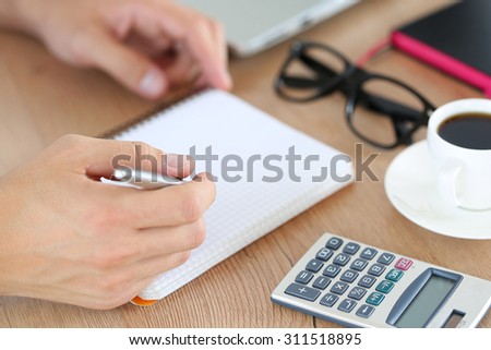 Male hand holding silver pen ready to make note in opened notebook. Businessman or employee at workplace writing business ideas, plans or tasks at personal organizer. Office life or education concept