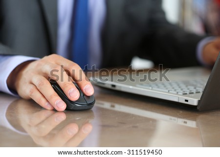 Hands of businessman in suit holding computer wireless mouse working with notebook pc. Working with computer, internet surfing, entertainment or business concept