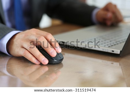 Hands of businessman in suit holding computer wireless mouse working with notebook pc. Working with computer, internet surfing, entertainment or business concept