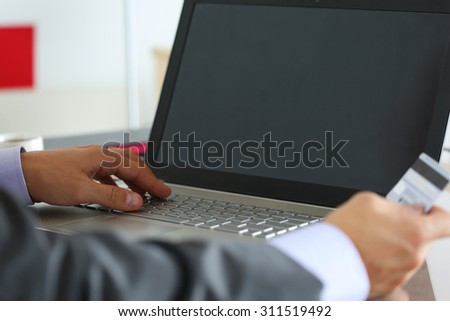 Hands of businessman in suit holding credit card and making online purchase using notebook pc. Shopping, consumerism, delivery or internet banking concept. Anti-fraud and financial security concept