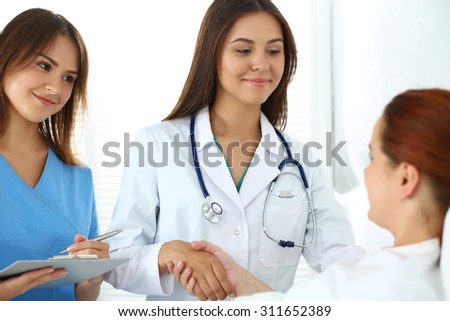 Female doctor shaking hands with patient lying in bed. Greeting and cheering gesture. Thankful handclasp for excellent treatment. Medical care or insurance concept. Physician ward round