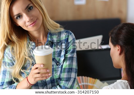 Two female designers in office drinking morning tea or coffee. Coffeebreak during hard working day. Employee woman holding cup of hot beverage. Creative people or advertising business concept