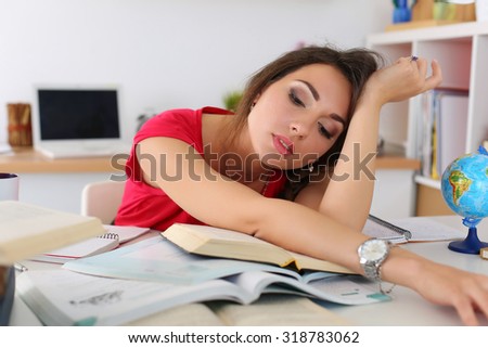 Tired young female student in red dress lying on pile of book dreaming. Bored woman trying make herself study at workplace suffering because of exam deadline concept. Education and self development