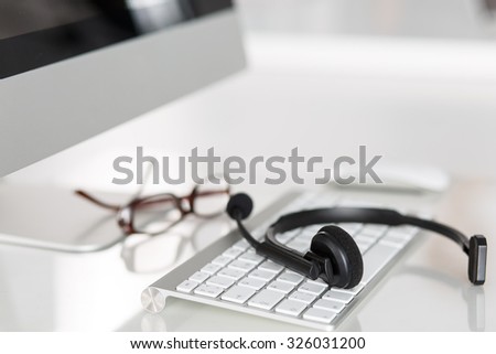 Call center service operator empty working place. Headset, glasses, keyboard and monitor at helpdesk employee workplace. Effective and efficient business information, help and support concept