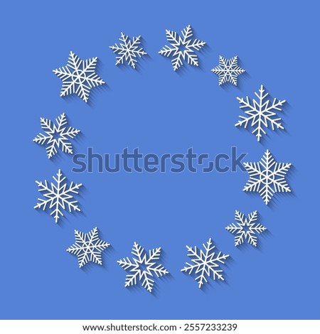 Wreath made of white snowflakes on blue background, copy space in the middle. Abstract round Christmas wreath, snow in a circle and circular array, flat lay and top view.