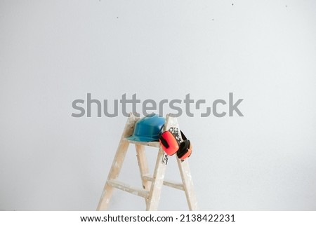 Foto Bild Leiter, blauer Schutzhelm und Ohrenschützer auf der Baustelle. Heimwerken, Renovierung